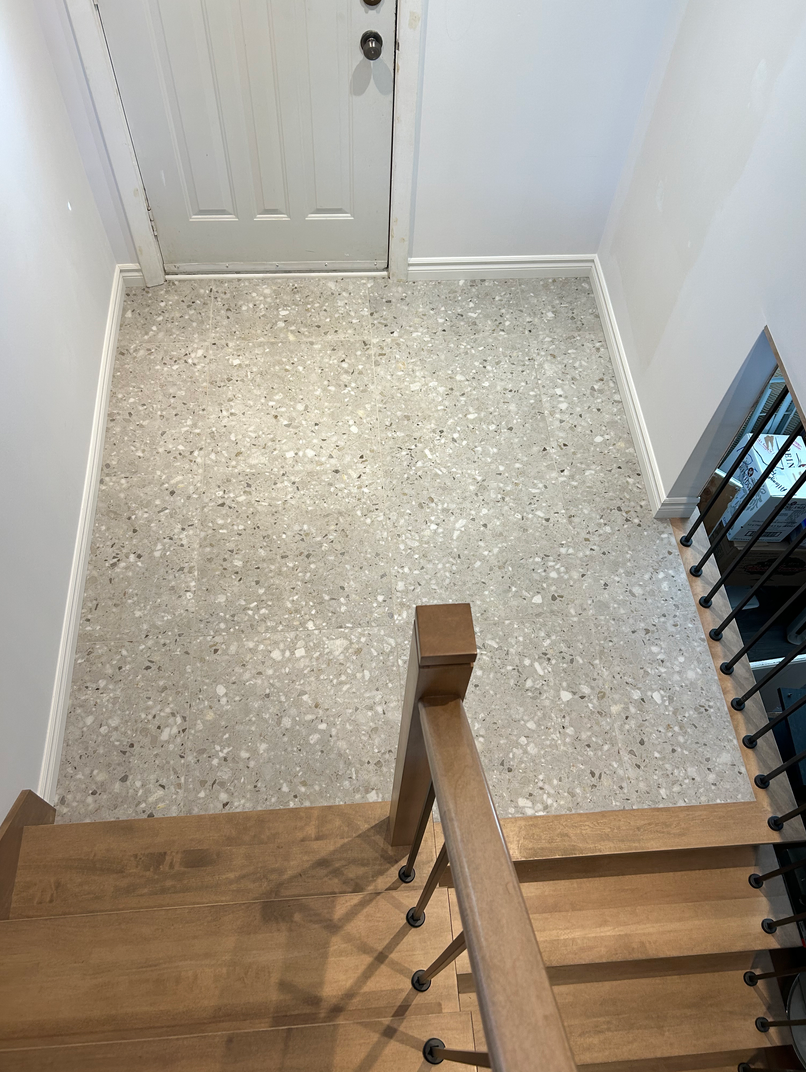 Vue aérienne d'un escalier avec une rampe en bois et un sol en terrazzo.