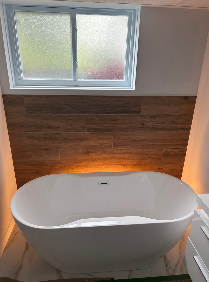 Une baignoire blanche se trouve dans une salle de bain à côté d'une fenêtre.