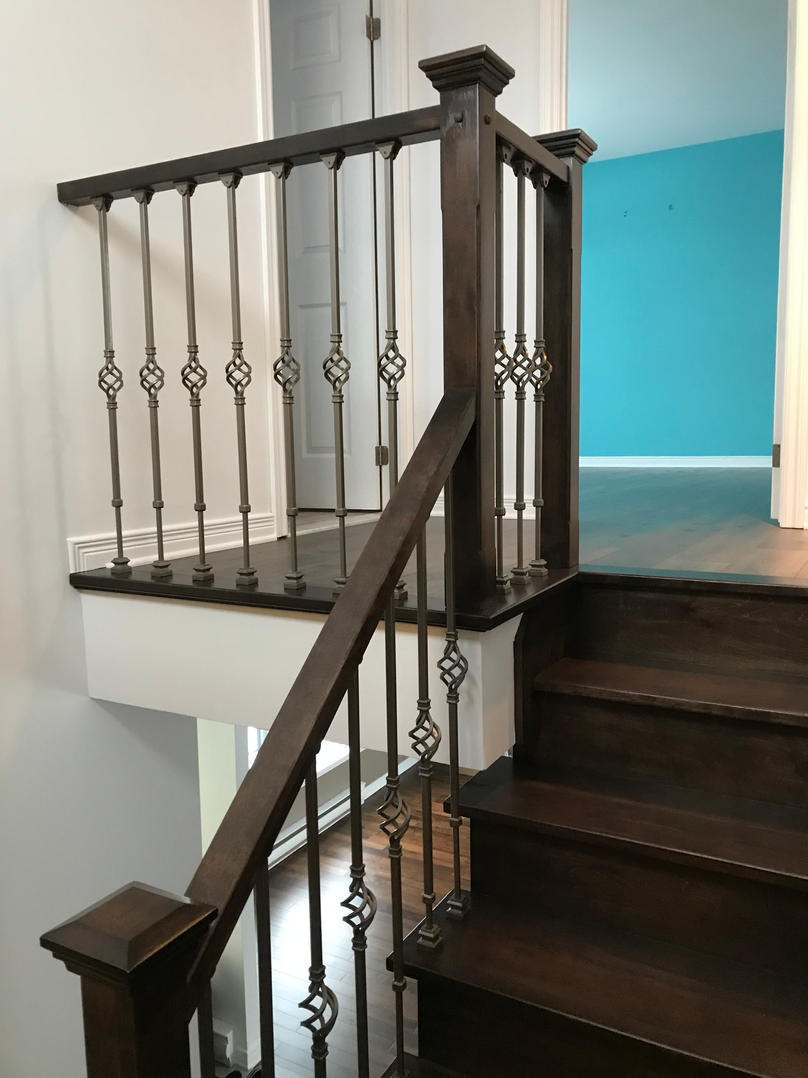 Un escalier en bois avec une rampe en fer forgé dans une maison.