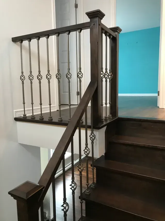Un escalier en bois avec une rampe en fer forgé dans une maison.