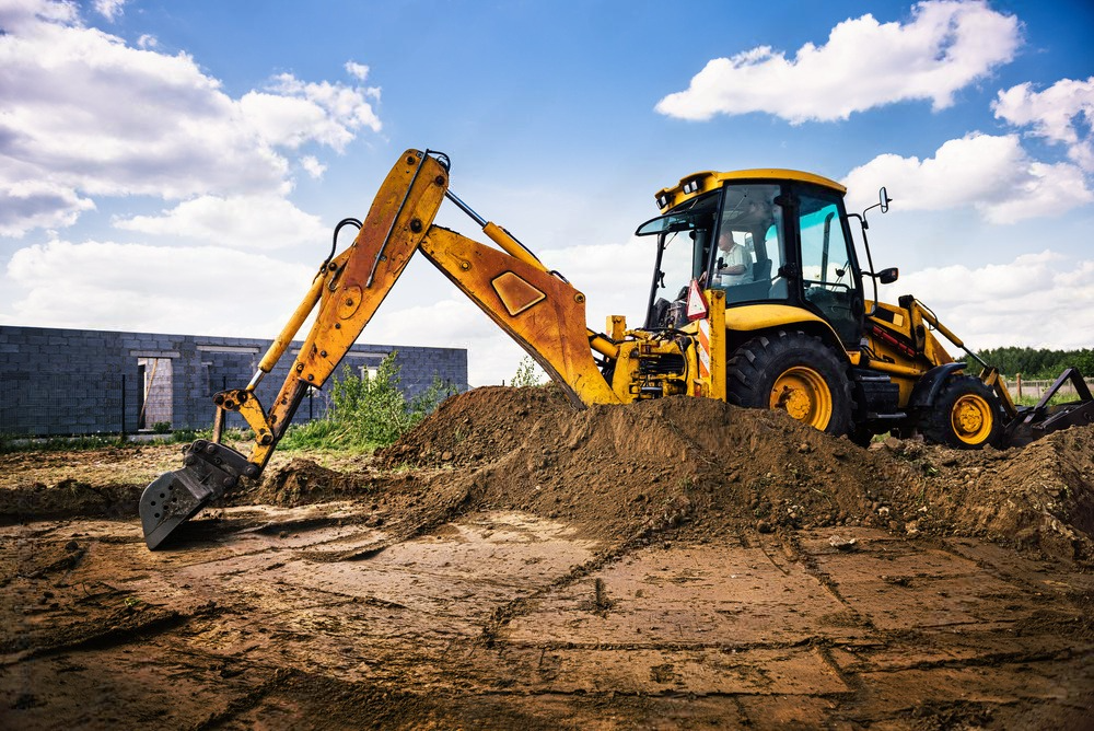 A yellow excavator is digging a hole in the dirt on a construction site.
