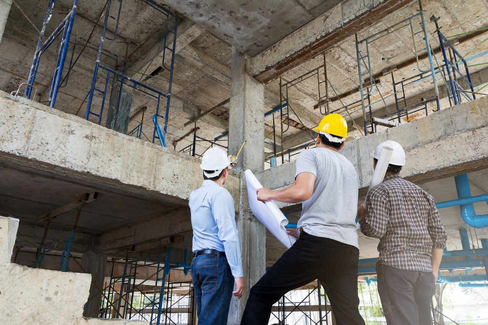 A group of construction workers are looking at a blueprint at a construction site.