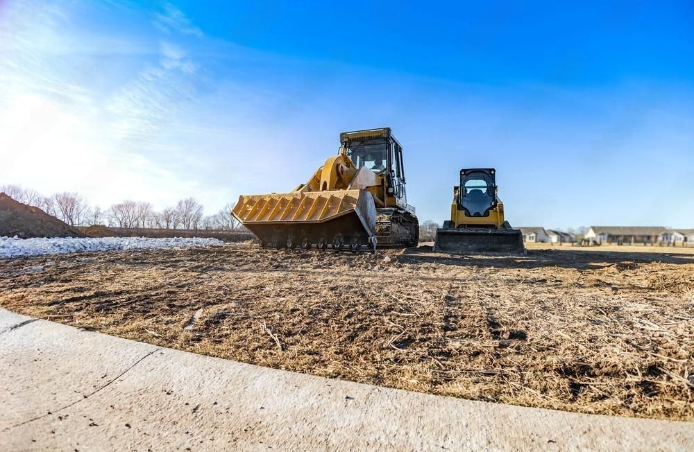 Two bulldozers are working on a dirt field.
