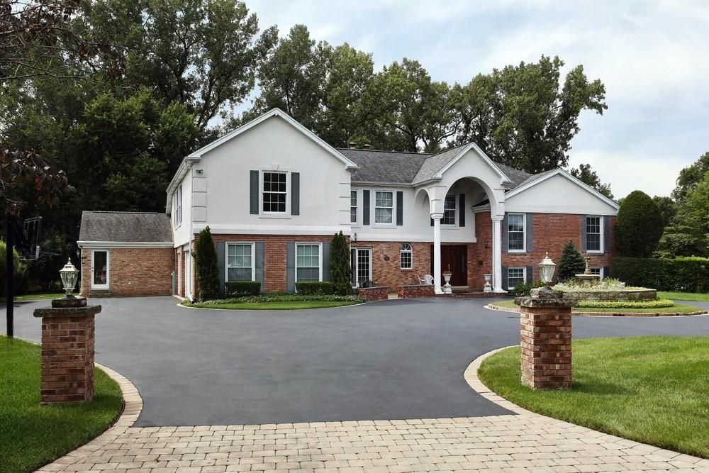 A large white house with a brick driveway leading to it