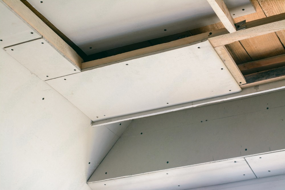 A ceiling is being built with drywall and wood.