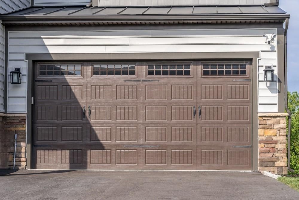 A large brown garage door is sitting in front of a house.