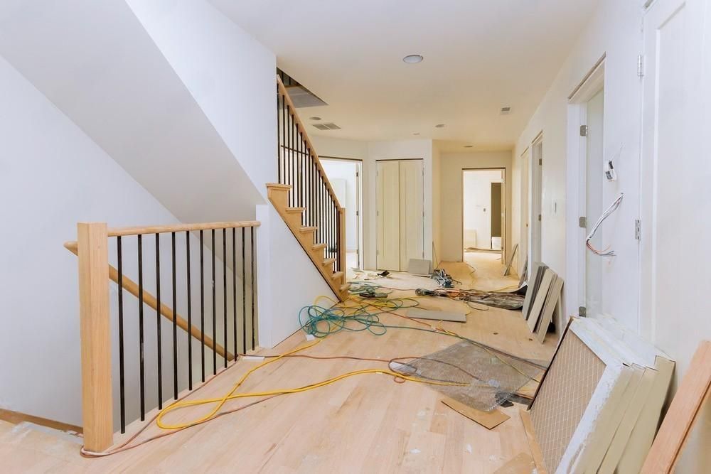 A hallway in a house under construction with wooden floors and stairs.