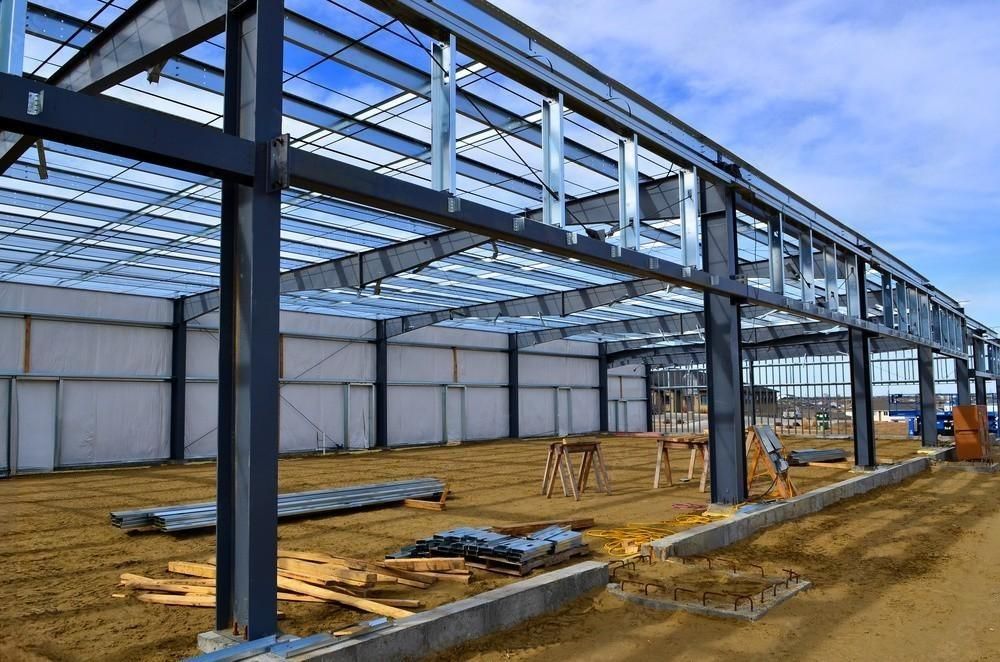 A large metal structure is being built on top of a dirt field.
