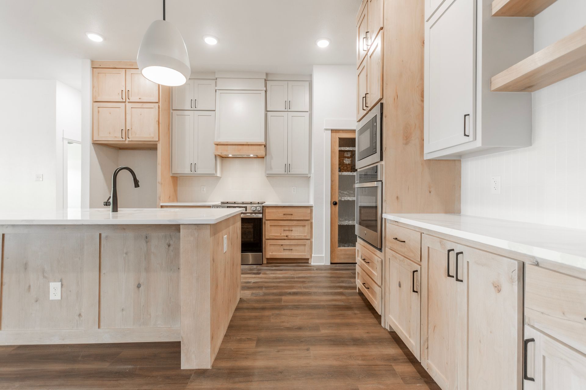Modern kitchen with white and wood cabinetry, island, and appliances.