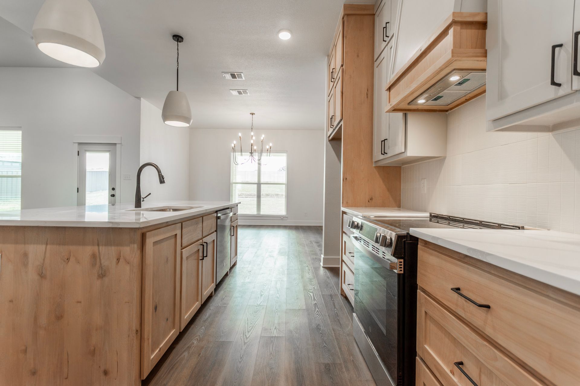 Modern kitchen with light wood cabinets, white countertops, and stainless steel appliances.