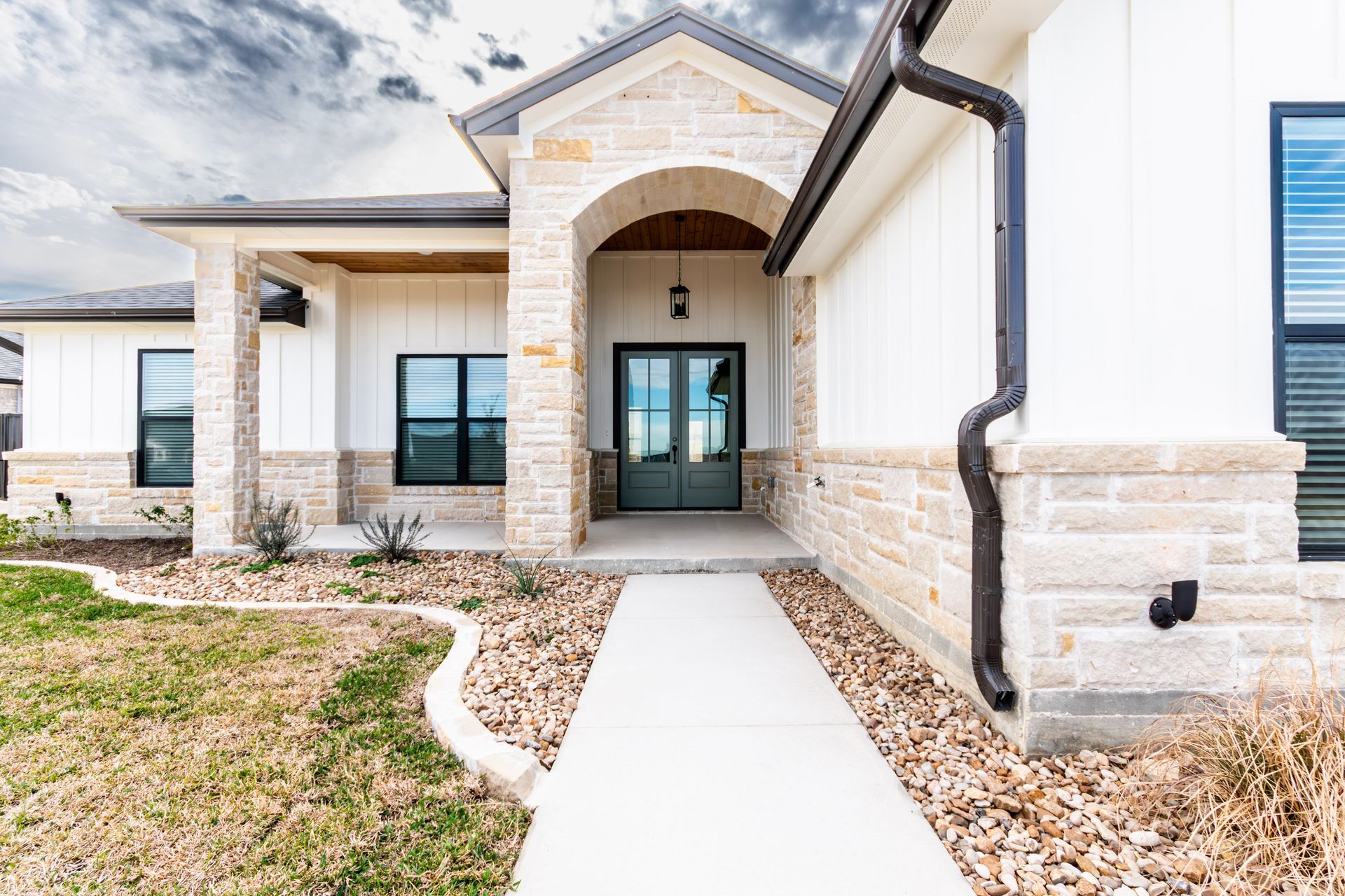 Modern home exterior with white siding, stone accents, and a covered entry.