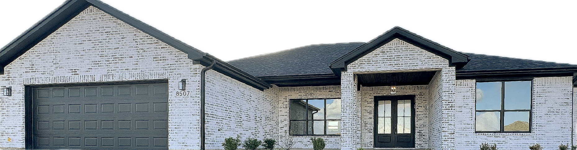 Stone-clad house with black roof and garage door, windows, and a double door entrance.