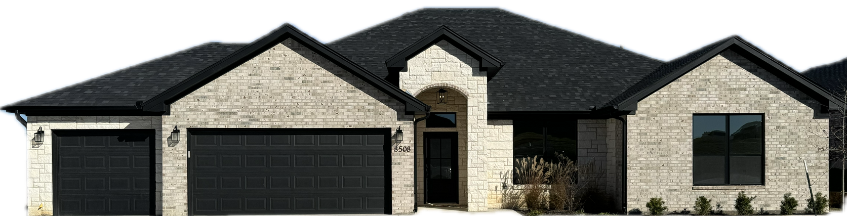 A modern house with a light stone facade and dark roof and garage doors.
