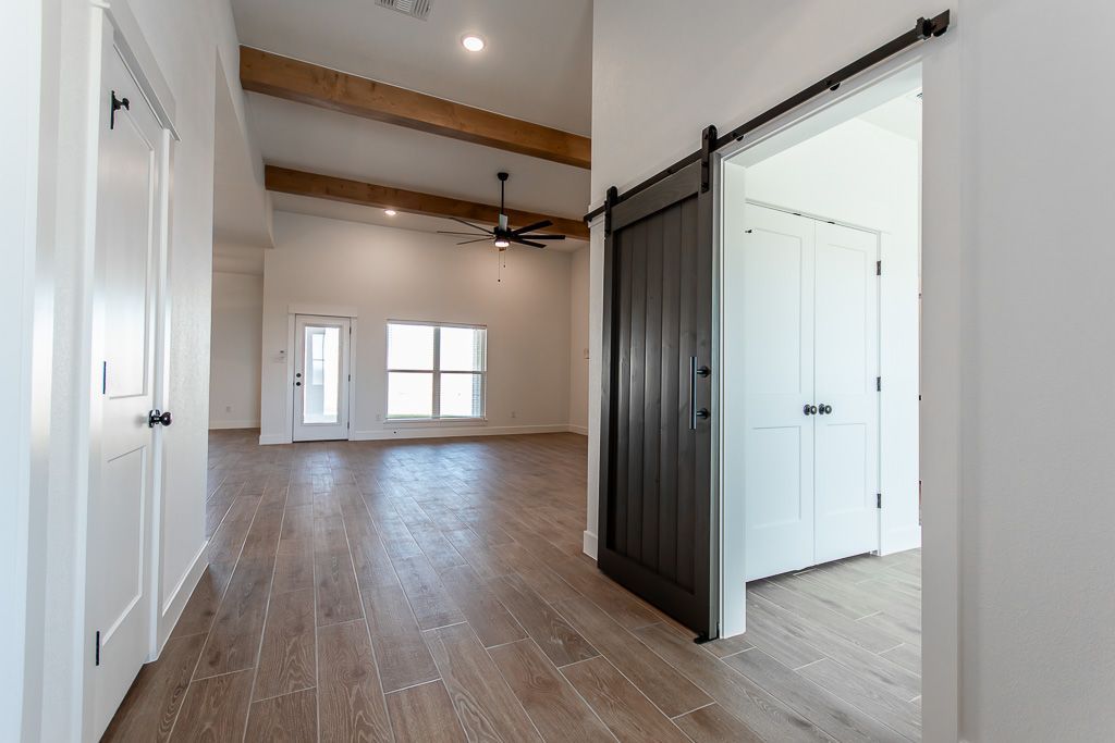 Interior hallway with wooden floor, white walls, and a barn door.