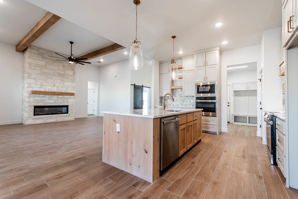 Modern kitchen with island and appliances; living room with fireplace and hardwood floors.
