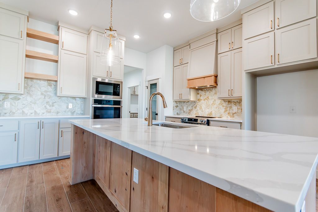 Spacious kitchen with a large island, white cabinets, marble countertop, and wood accents.