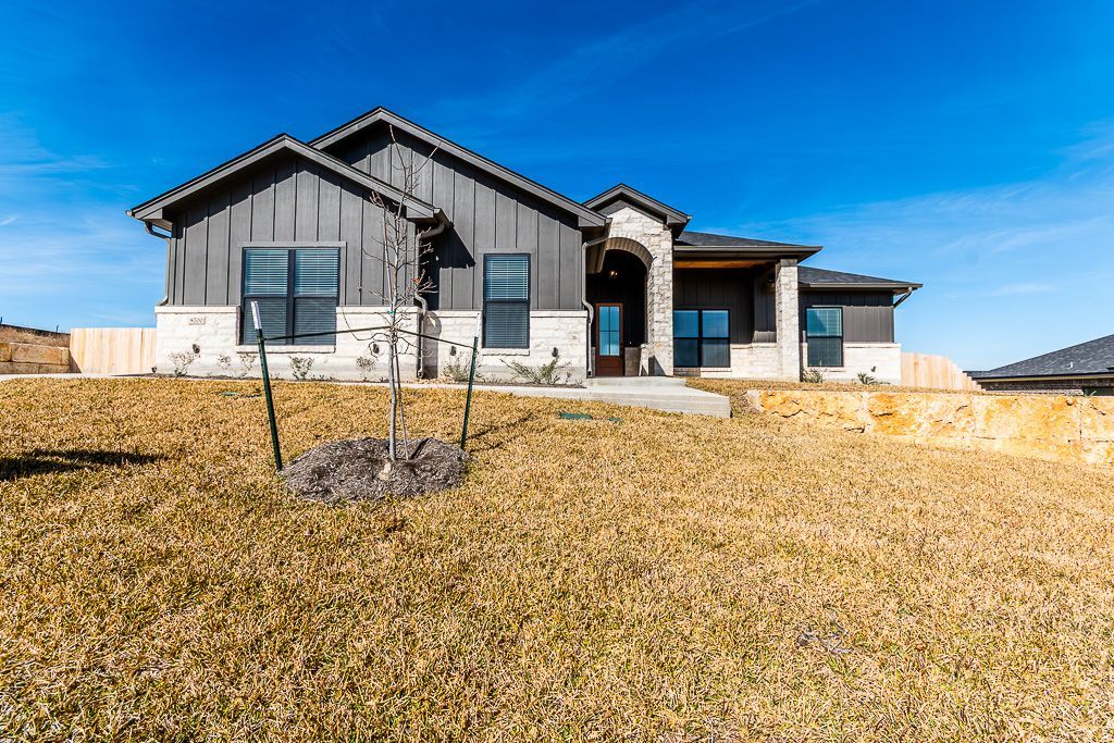 Modern home with gray siding, stone accents, and a blue sky.