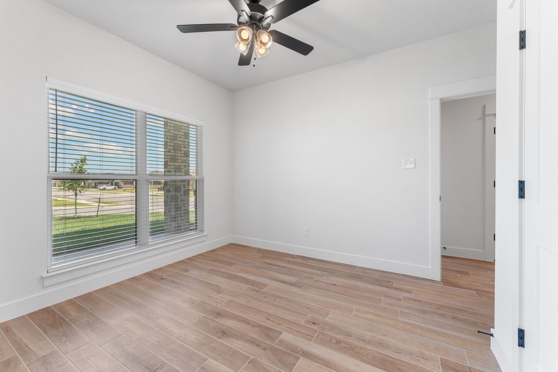 Empty room with wood floors, a window, and a ceiling fan.