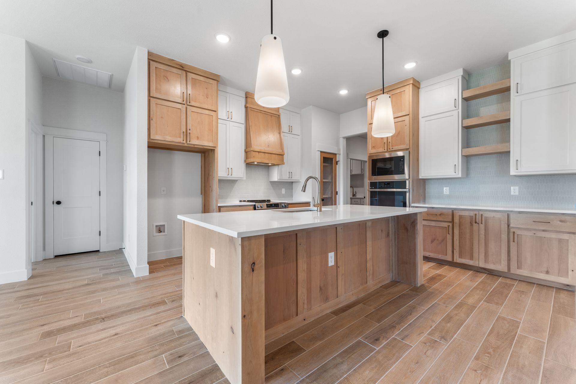 Spacious kitchen with wood cabinets, white countertops, and a large island with pendant lighting.