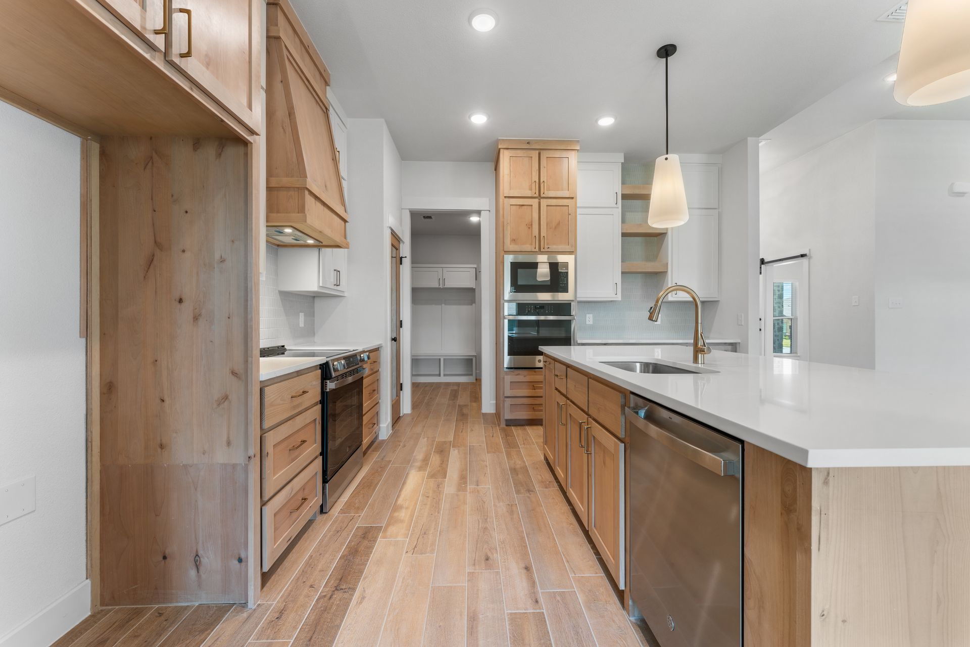 Light wood kitchen with island, stainless steel appliances, and white countertops.