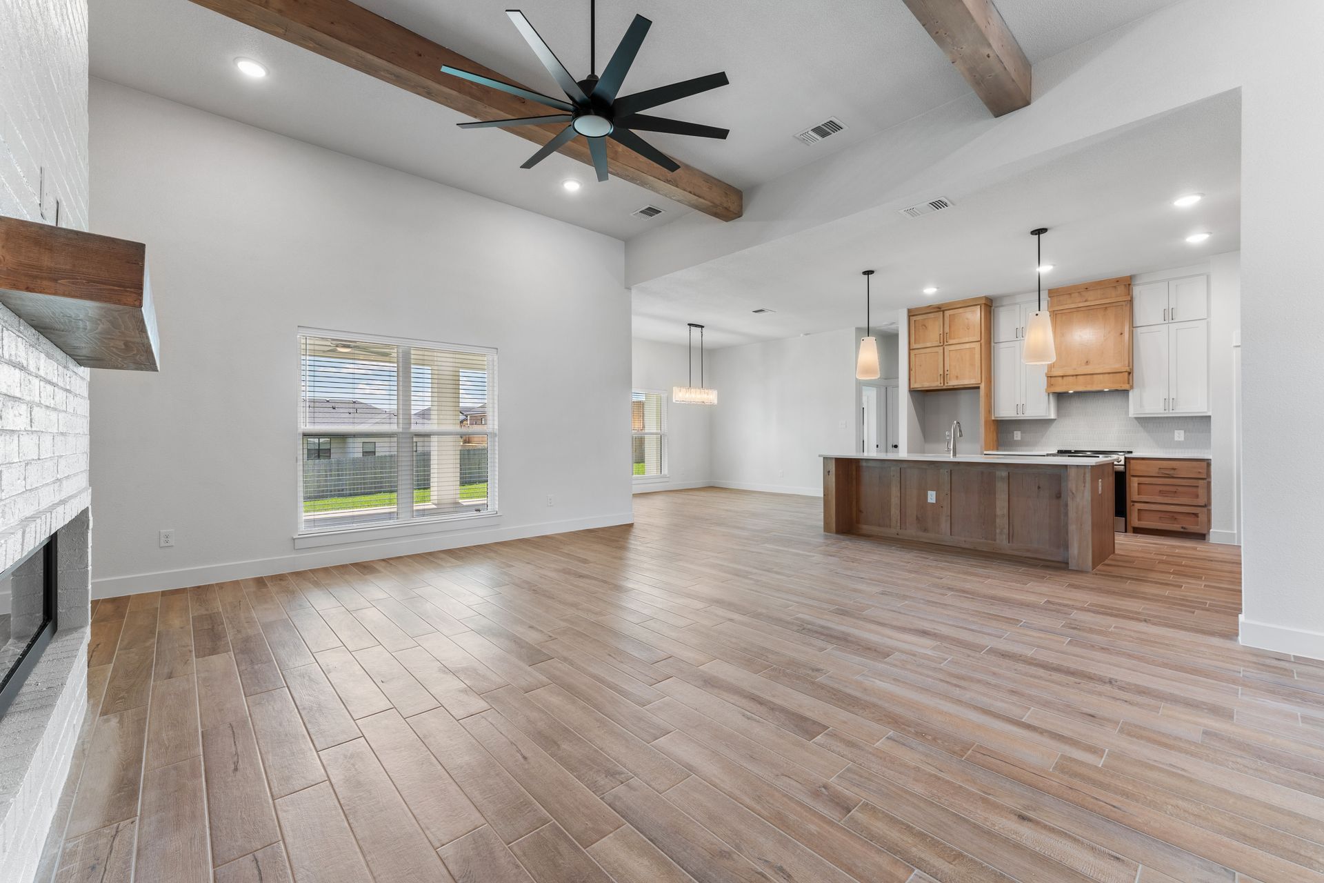 Open-concept living space with hardwood floors, high ceiling, kitchen, and large windows.