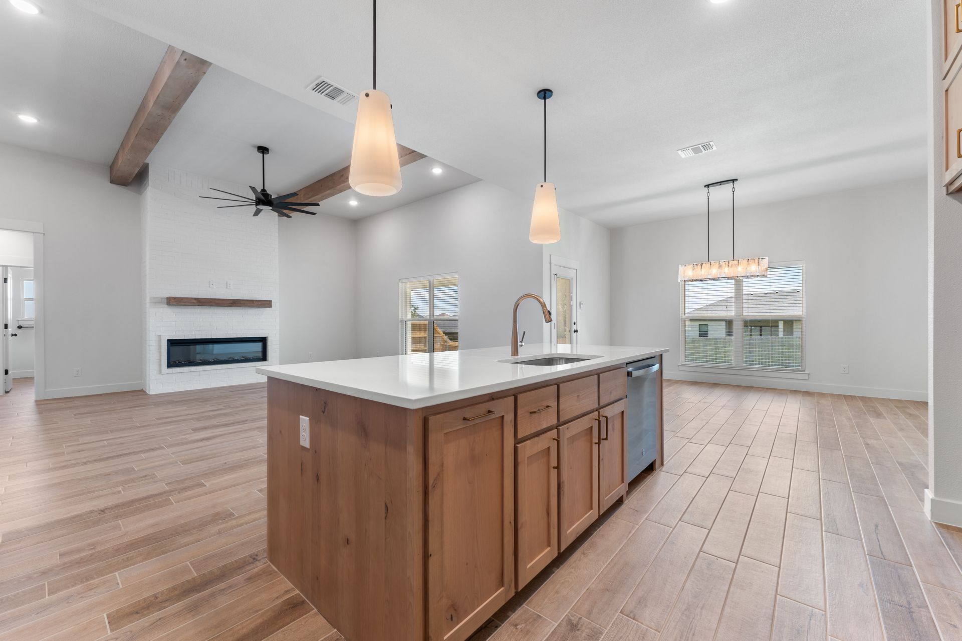 Spacious kitchen with island, fireplace, and light wooden floors.