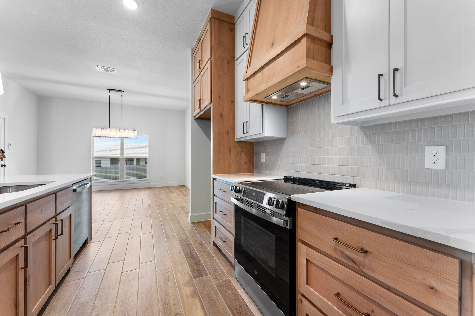 Modern kitchen with wood and white cabinets, stainless steel appliances, and wood flooring.