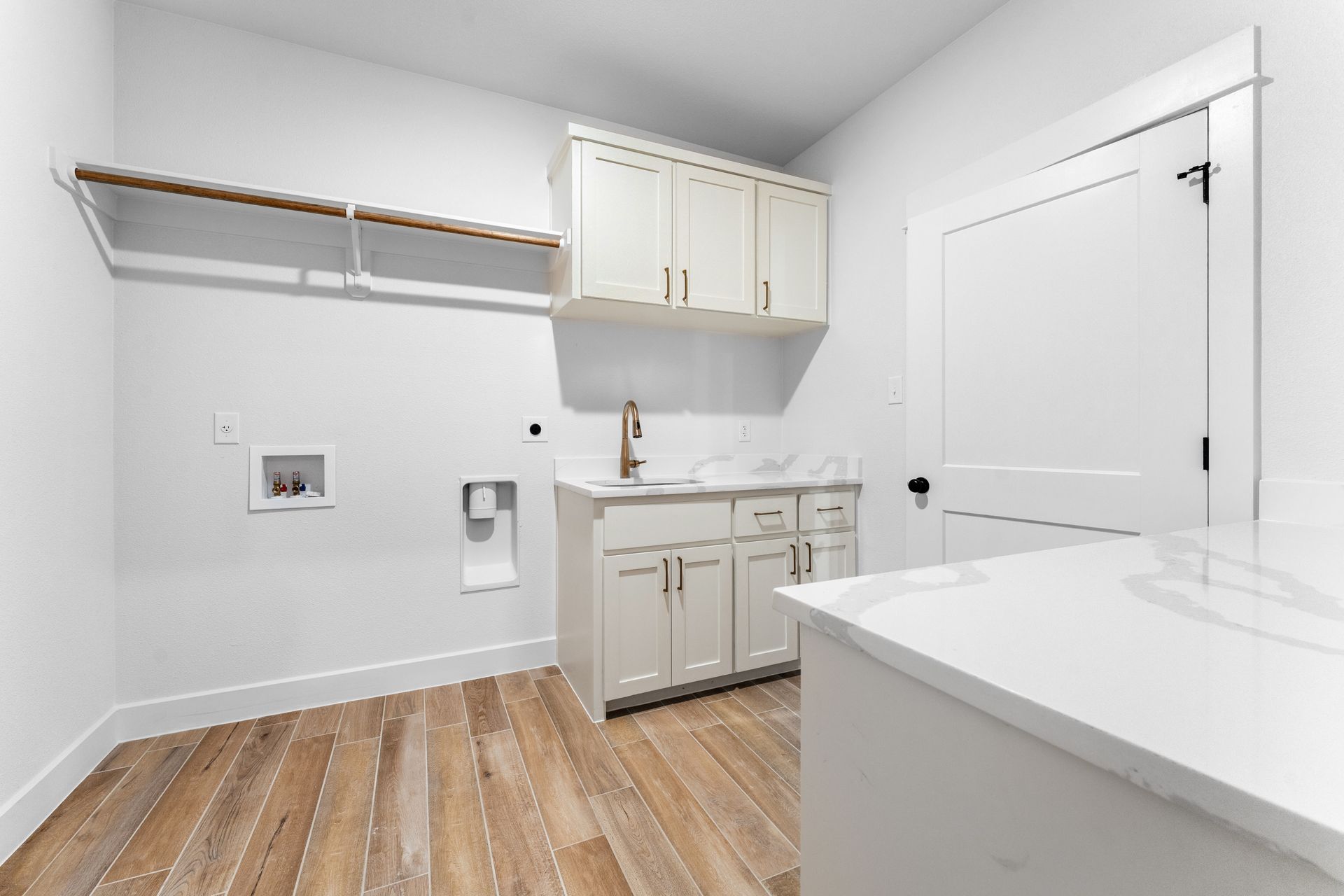 Laundry room with light wood floors, white cabinets, and a white countertop.
