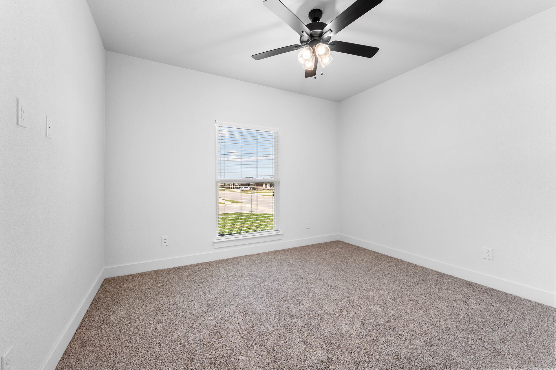 Empty room with carpet, window, ceiling fan, and white walls.