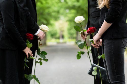 persone in piedi al funerale con i fiori