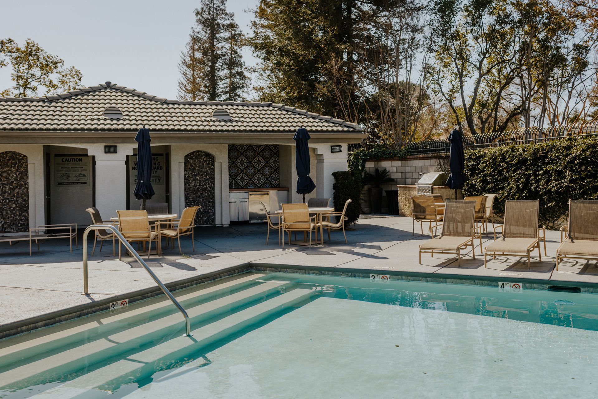 A large swimming pool surrounded by chairs and umbrellas
