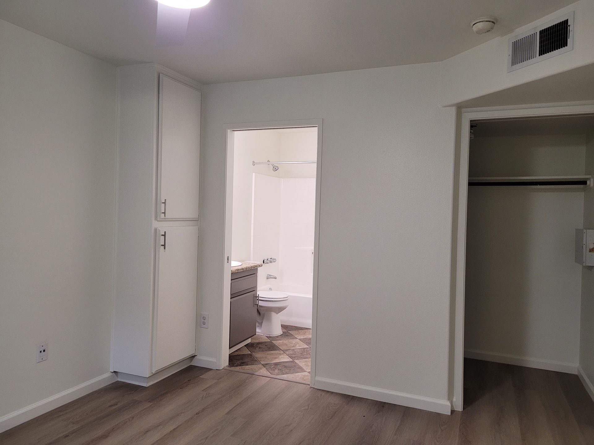 An empty bedroom with a bathroom and a closet.