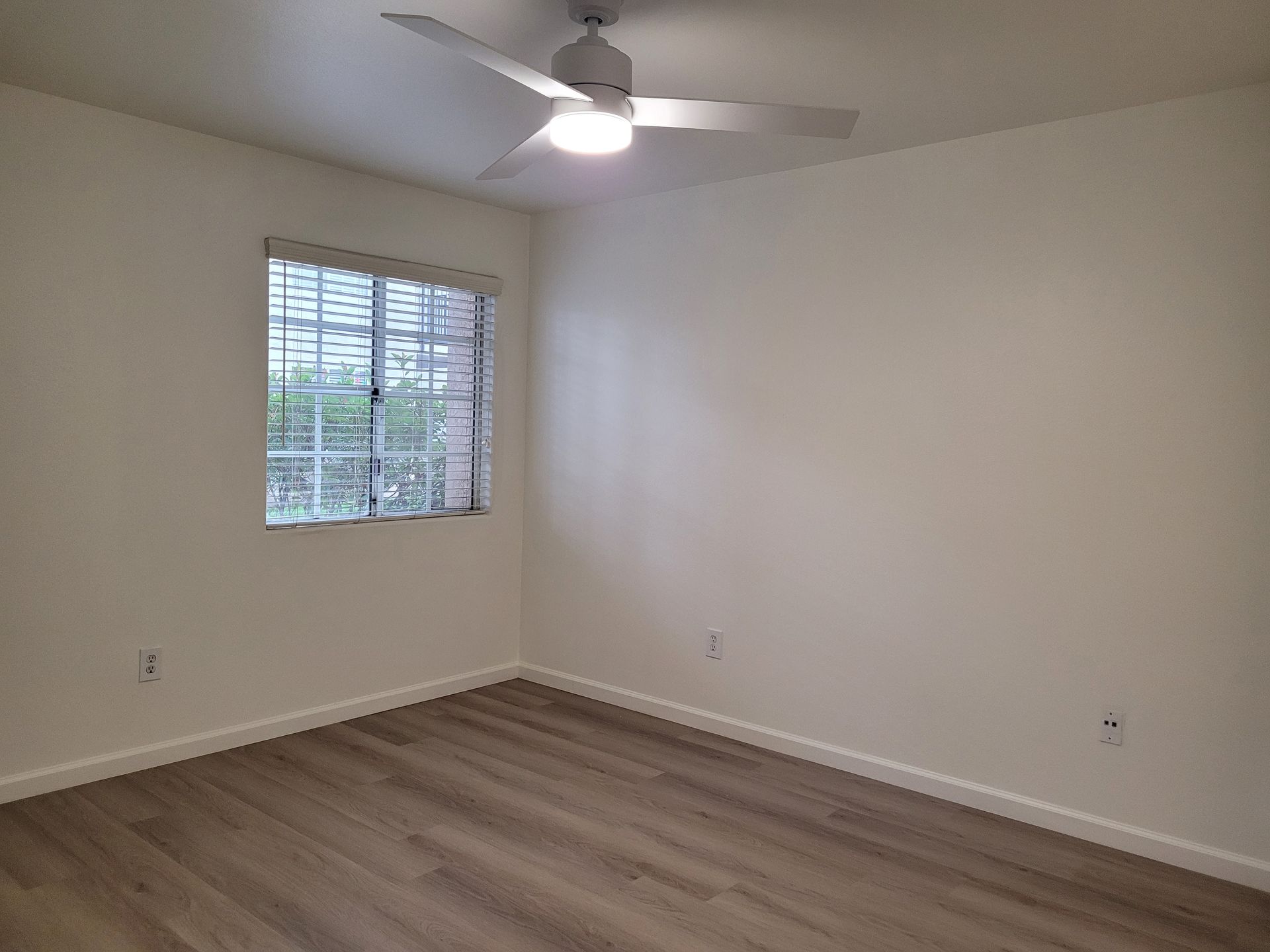 An empty bedroom with a ceiling fan and a window.