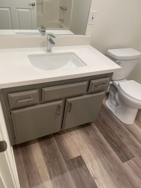 A bathroom with a sink , toilet and mirror.