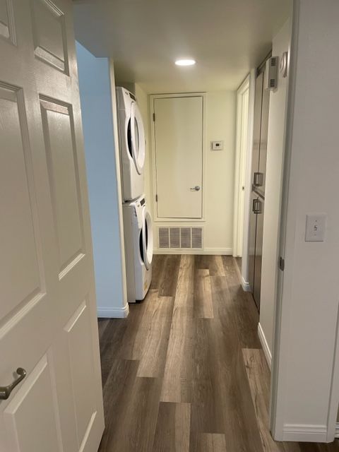 A hallway with a washer and dryer stacked on top of each other.