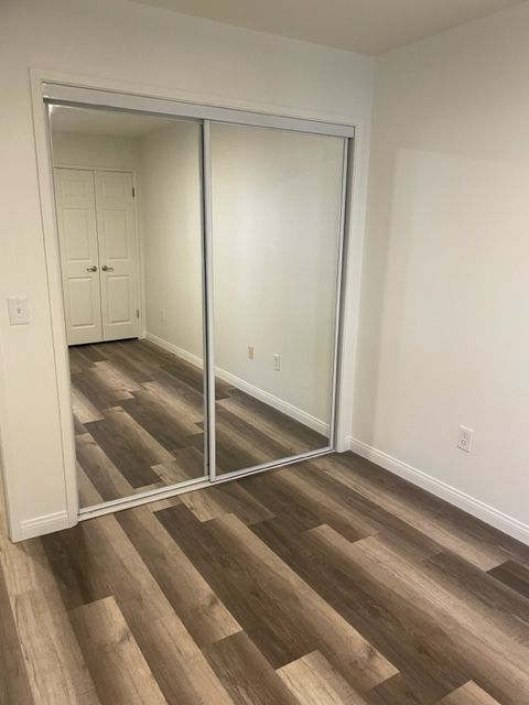 A bedroom with hardwood floors and sliding glass doors.