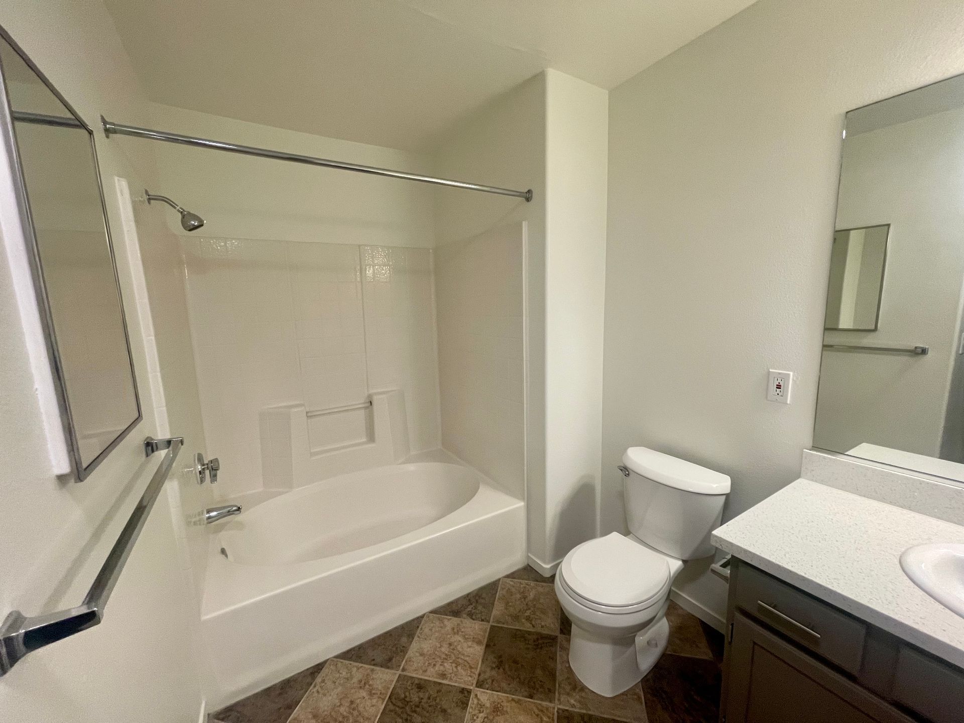 A bathroom with a tub , toilet , sink and mirror.