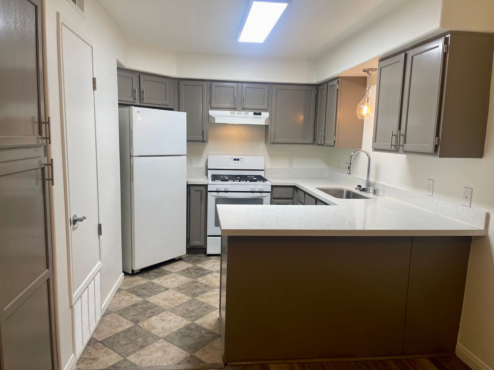 A kitchen with a refrigerator , stove , sink and cabinets.