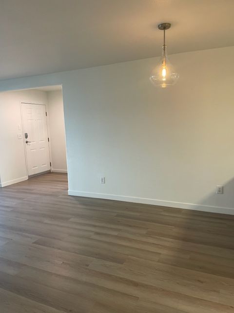 An empty living room with hardwood floors and white walls.