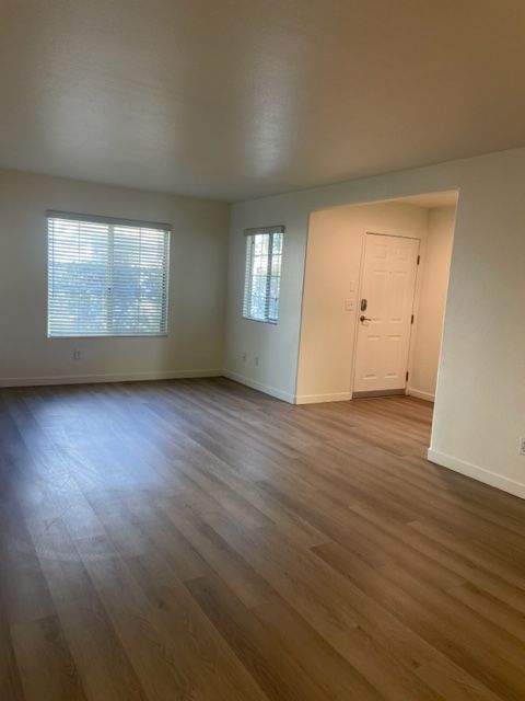 An empty living room with hardwood floors and a window.