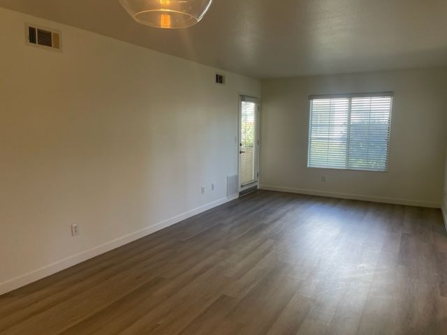 An empty living room with hardwood floors and a window