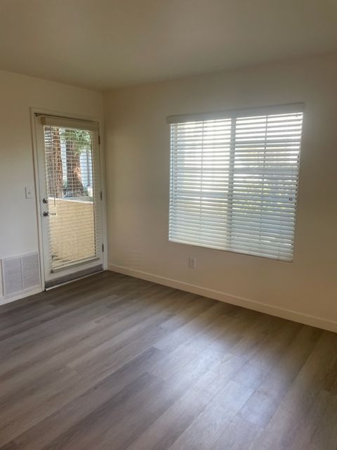 An empty living room with a sliding glass door and a large window.