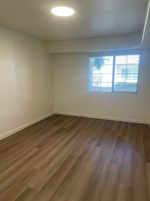 An empty room with hardwood floors and a window.