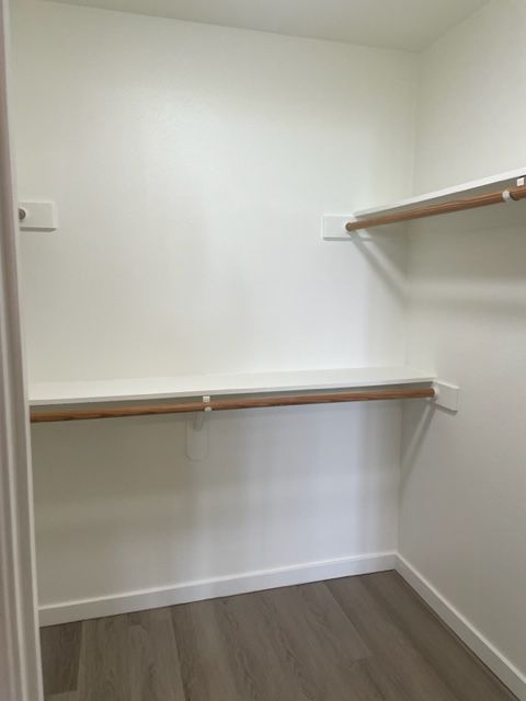 An empty walk in closet with wooden shelves and a wooden floor.