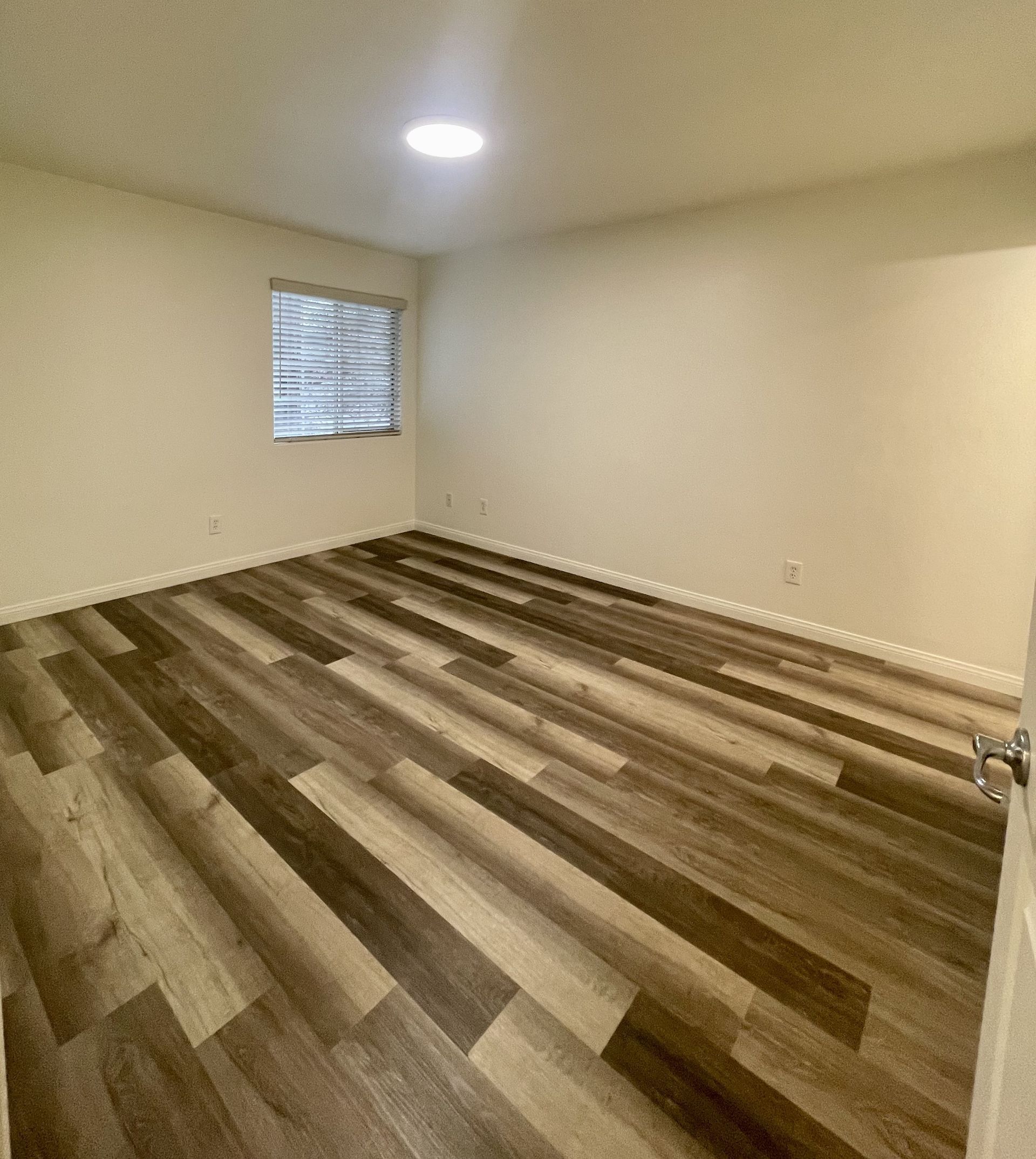 An empty room with a wooden floor and a window.