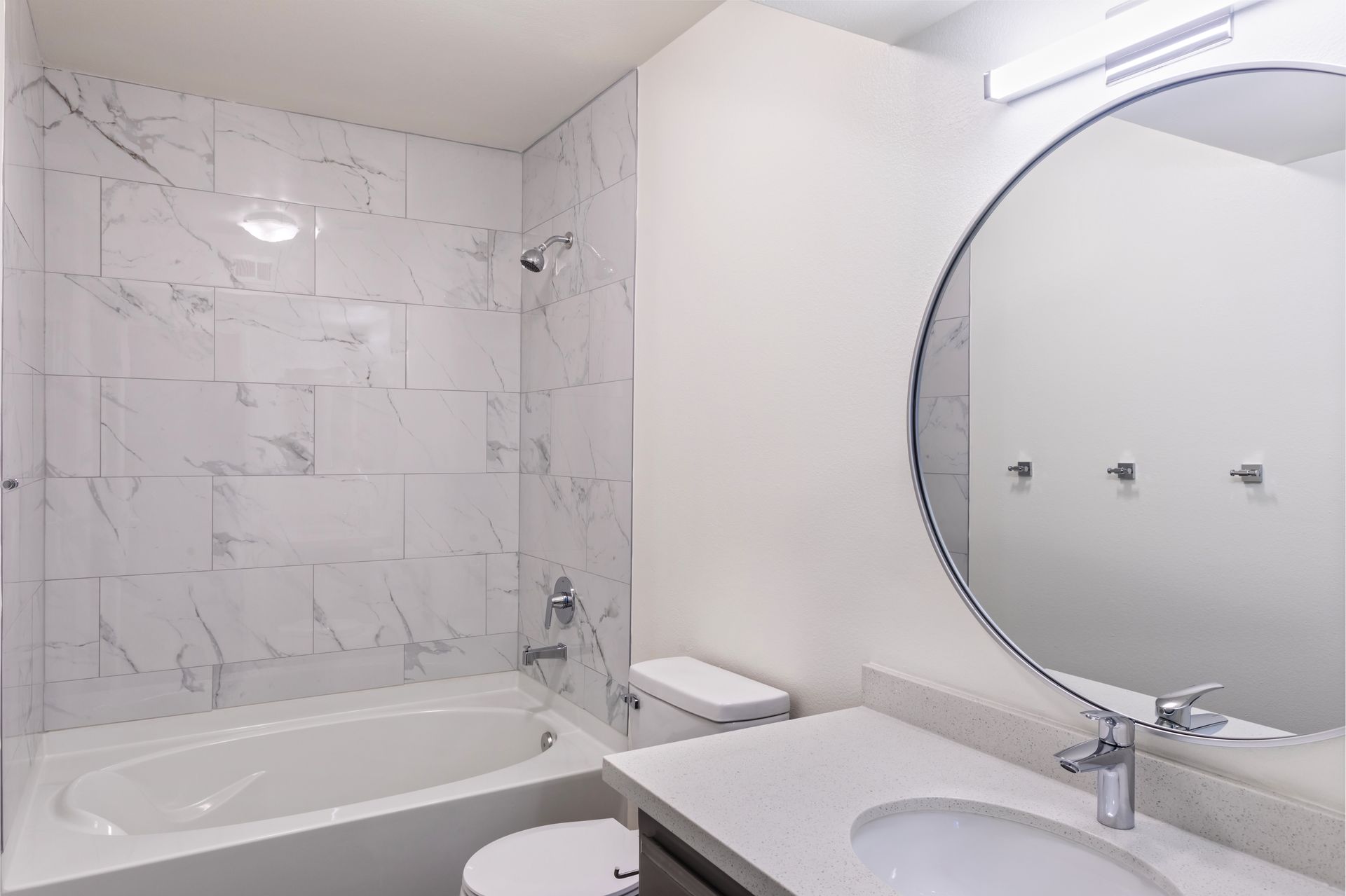 A bathroom with a tub , toilet , sink and mirror.