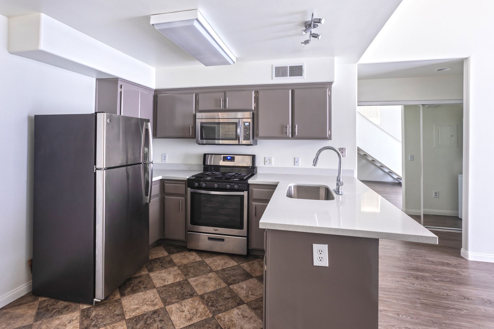 A kitchen with a refrigerator , stove , microwave and sink.