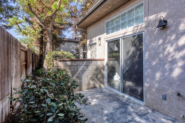 The backyard of a house with a sliding glass door and a fence.