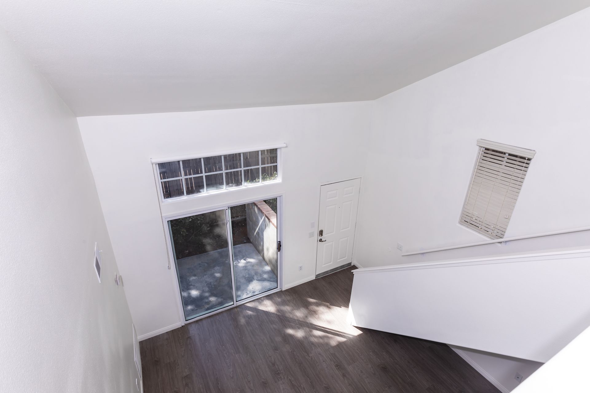 An empty room with a staircase and a sliding glass door