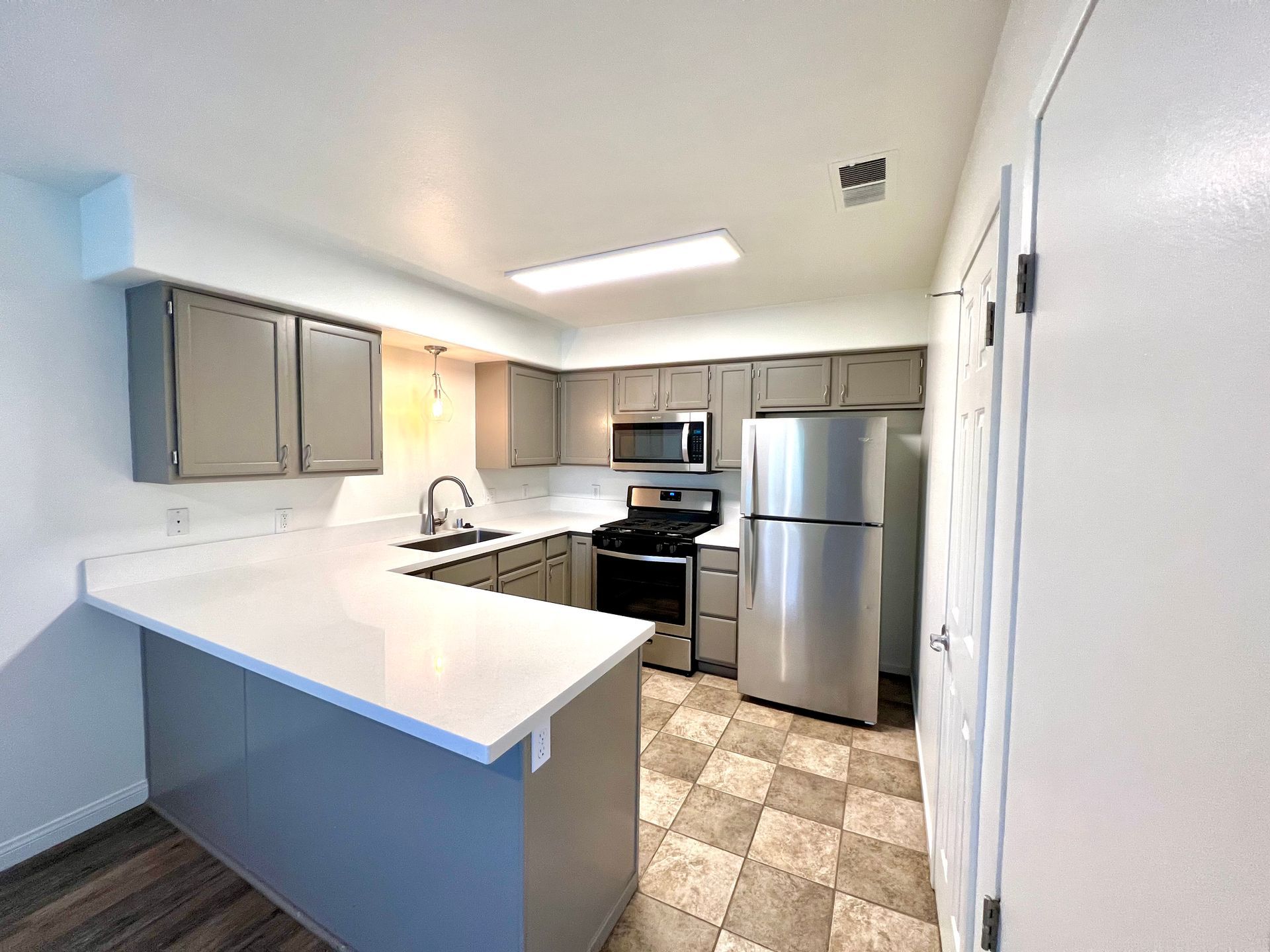 A kitchen with stainless steel appliances and gray cabinets.